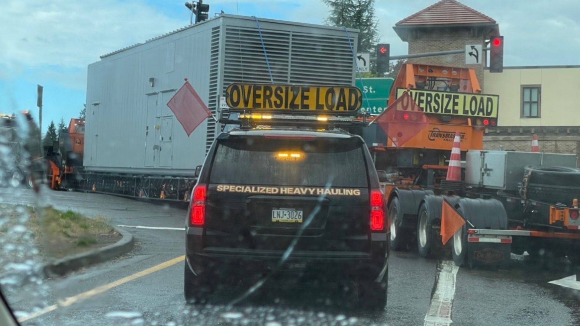 Cars driving on a multi-lane highway, concrete barrier, bridge in the background, daylight.