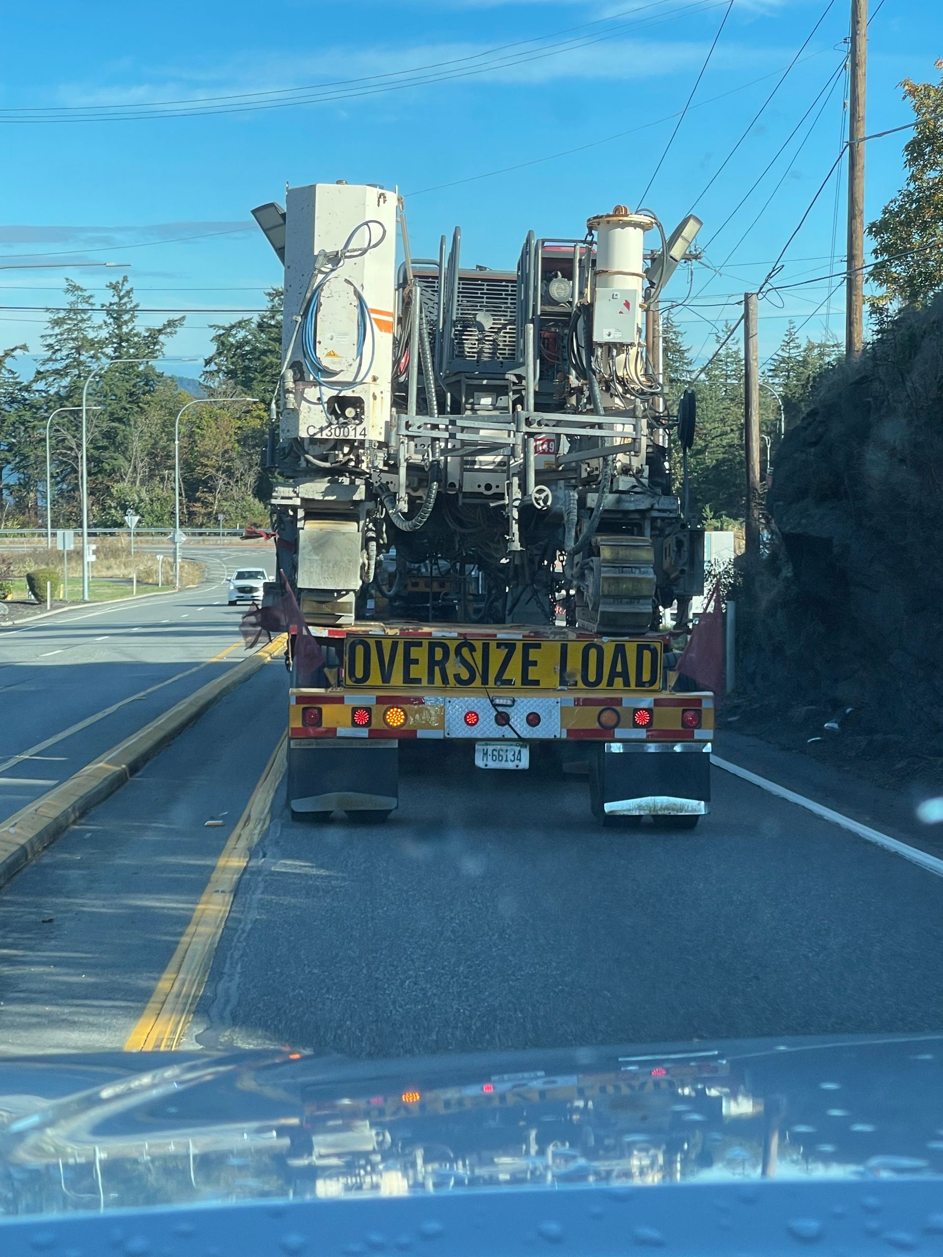 Truck hauling oversized road construction equipment on a highway, with 