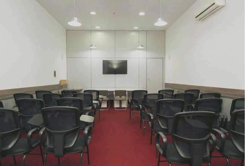Uma sala de aula com fileiras de cadeiras e uma televisão na parede: Hotel Bergozza