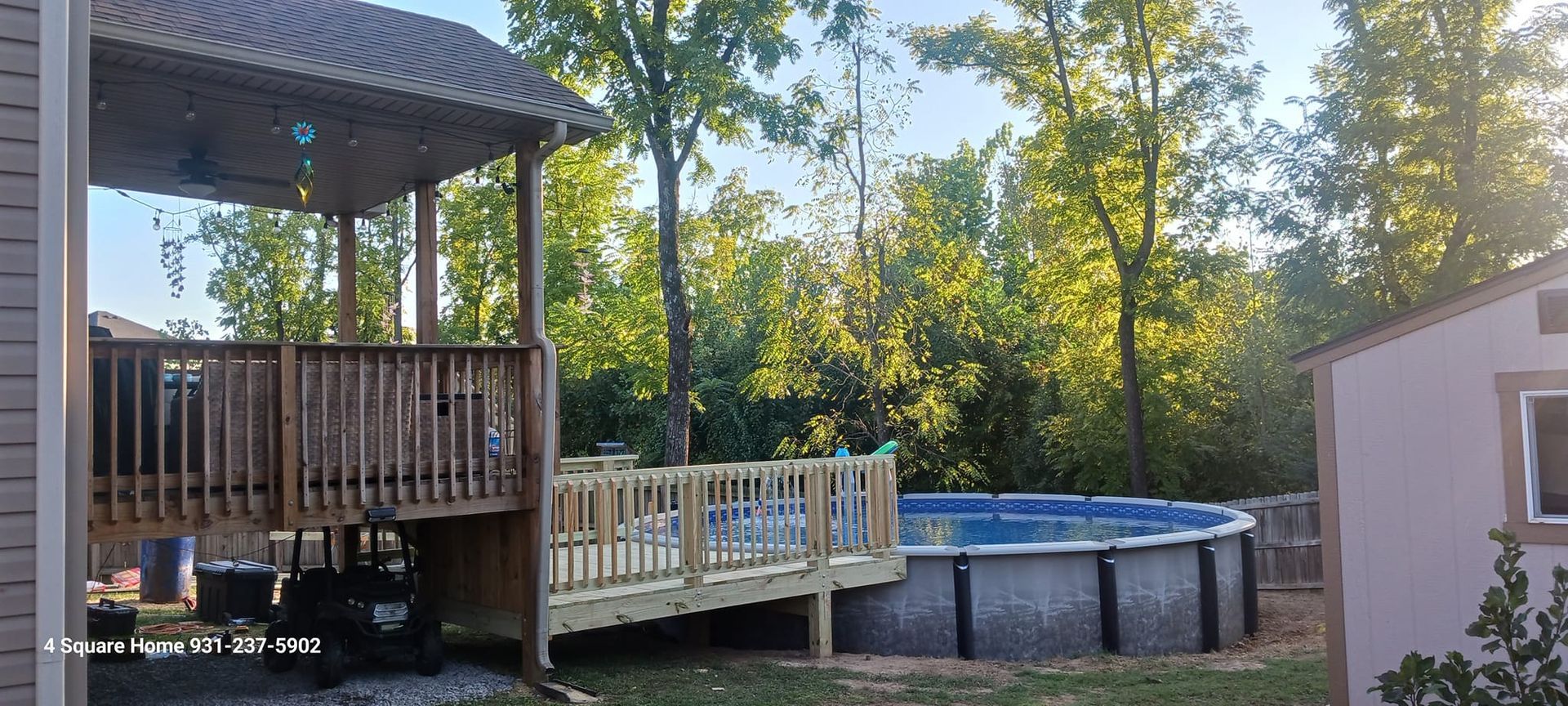 Wooden deck with ramp and gazebo overlooks a round above-ground pool and wooded area. A shed is visible.