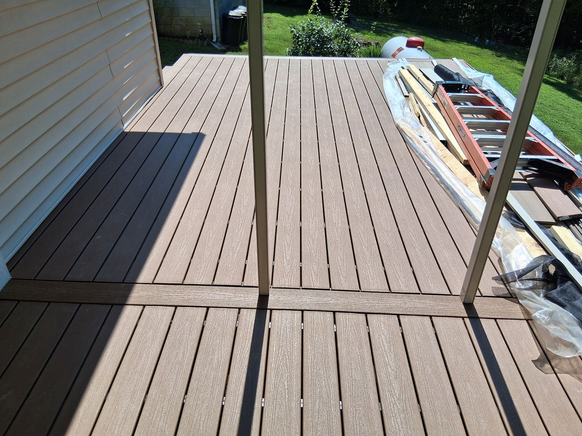 Brown composite deck with ladder and building materials.