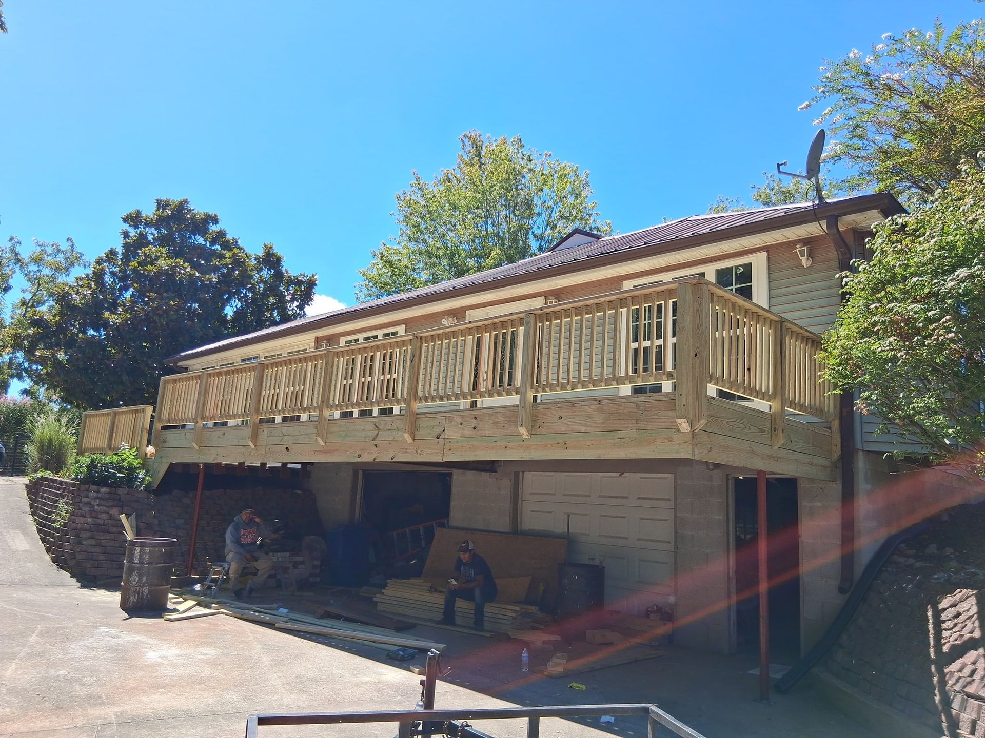 A newly constructed wooden deck on a house. Men are working underneath the deck on a sunny day.