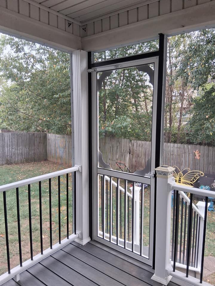 Screened porch with black railings, a black-framed screen door, and a view of a backyard with a fence.