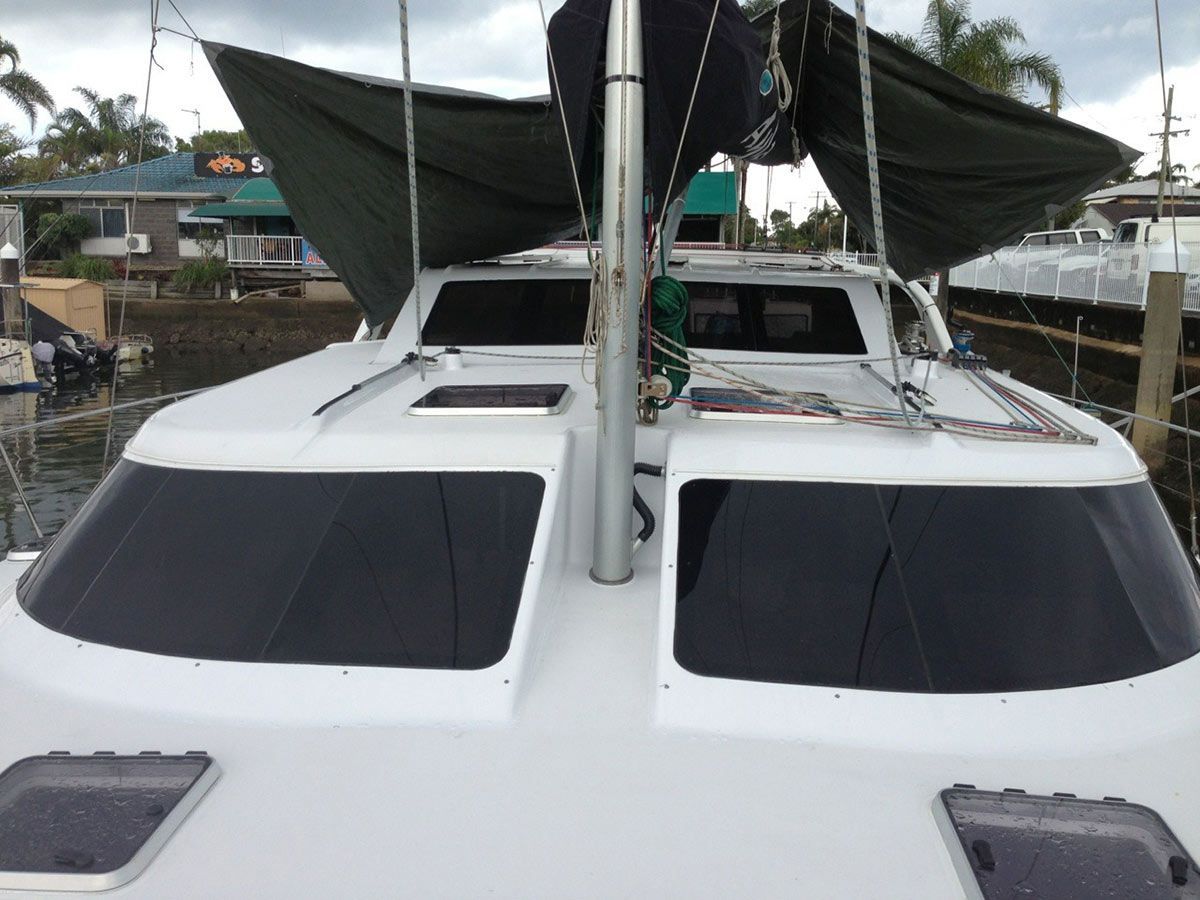 A White Boat with A Green Sail Is Docked at A Dock — Ashby Boat Builders In Buddina, QLD