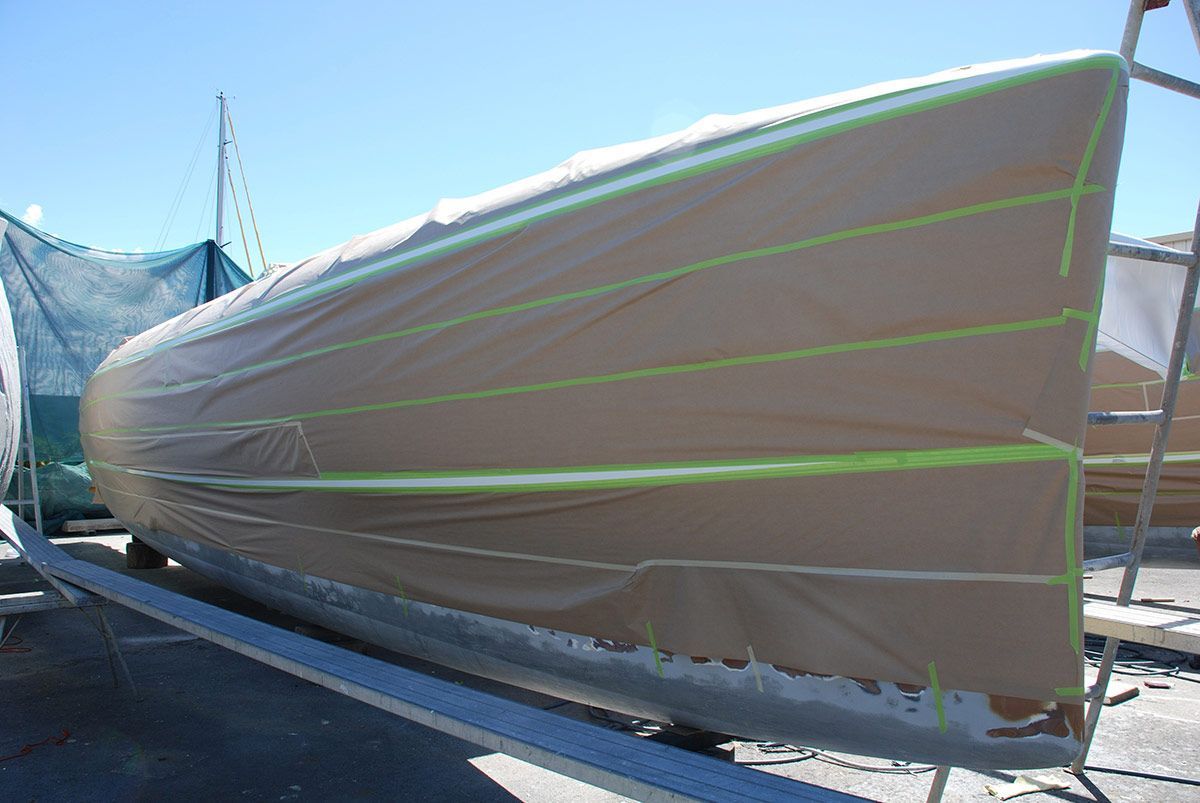 A Boat Is Covered in Plastic and Tape and Is Being Painted — Ashby Boat Builders In Buddina, QLD