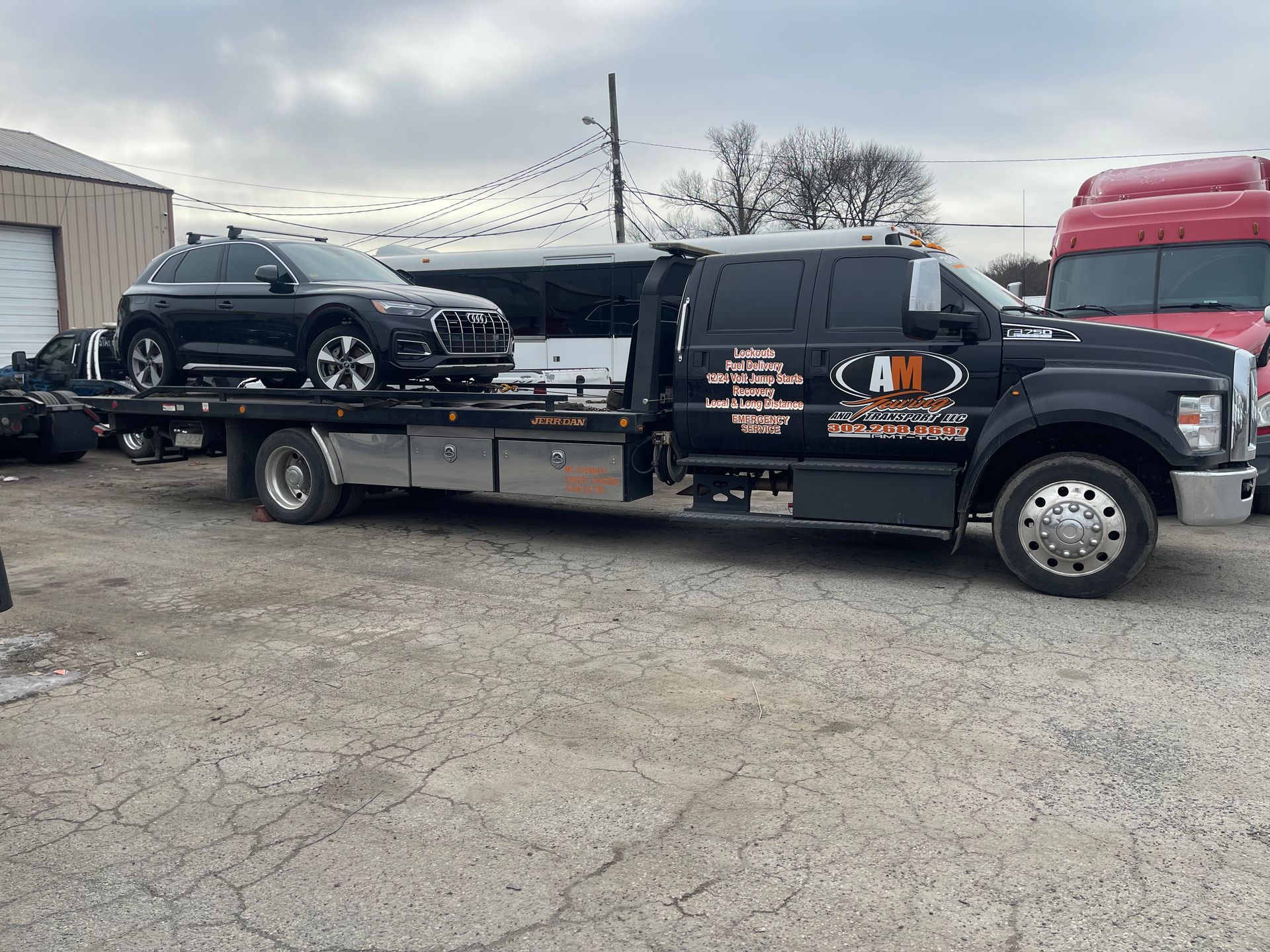 Black car being towed by a tow truck on a paved surface.