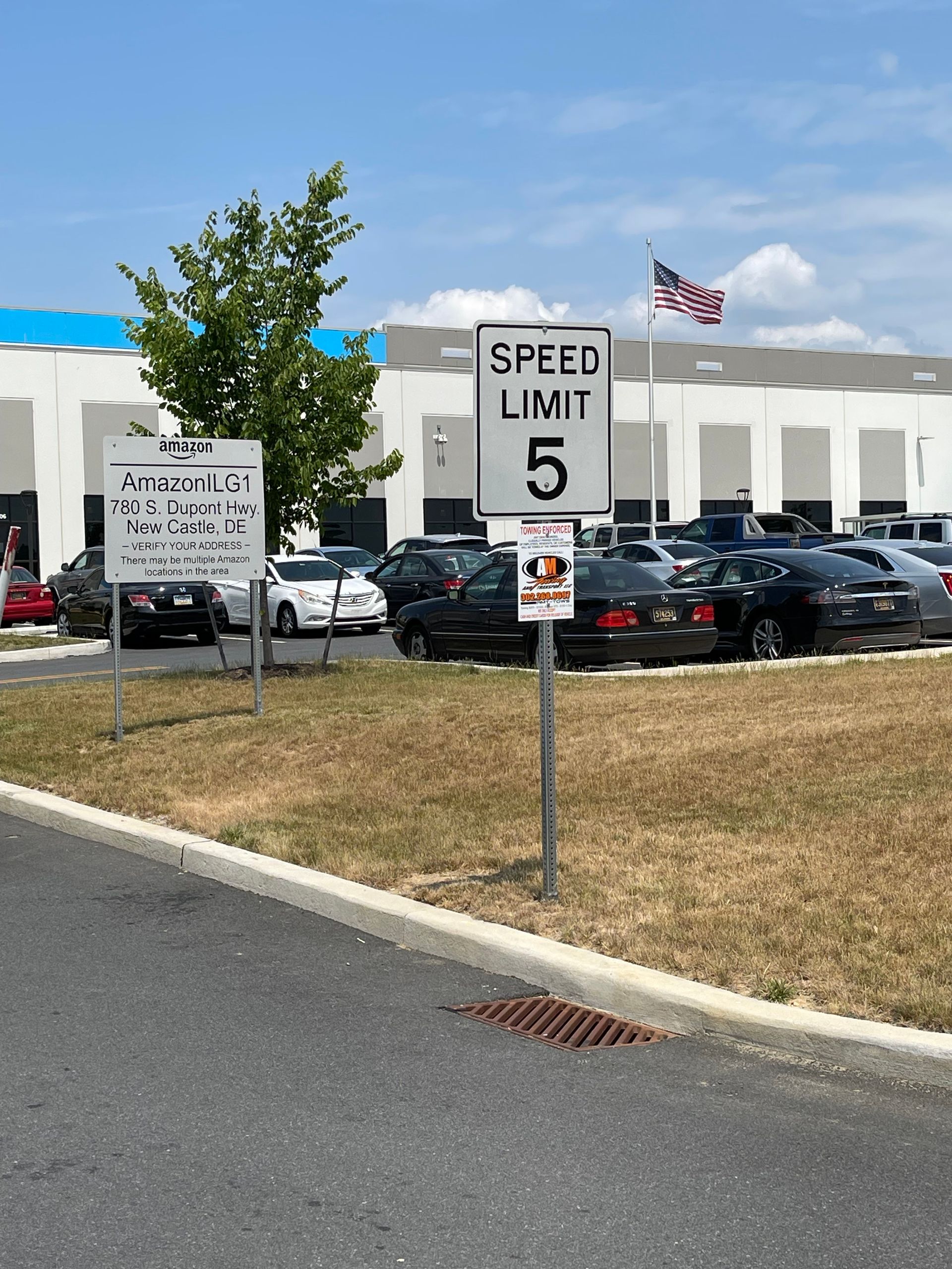 Speed limit 5 mph sign in a parking area with cars parked.