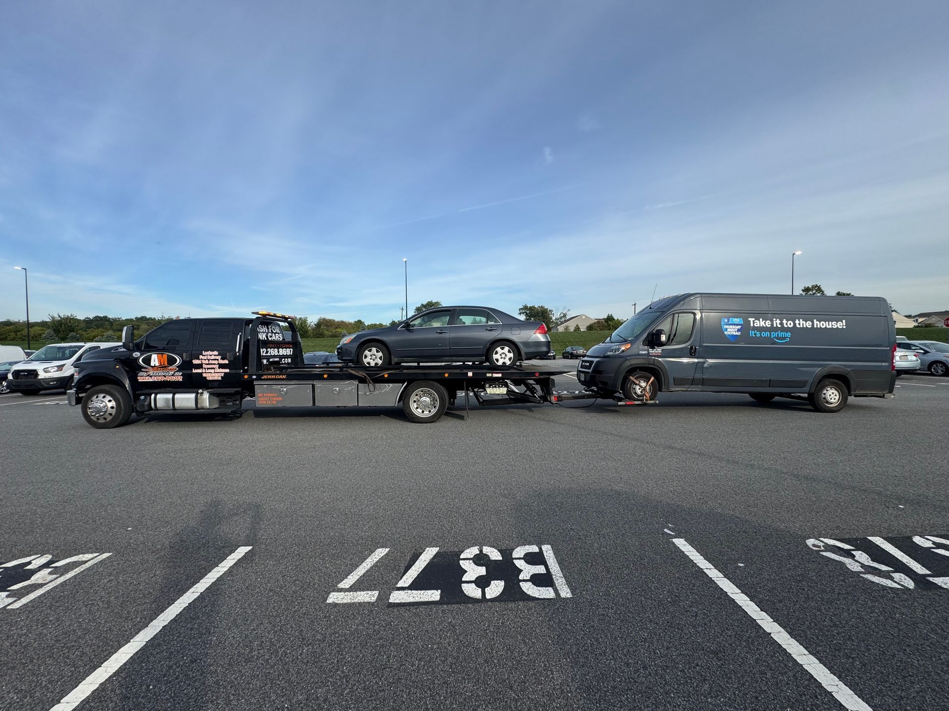 White car being towed by a tow truck on a road.
