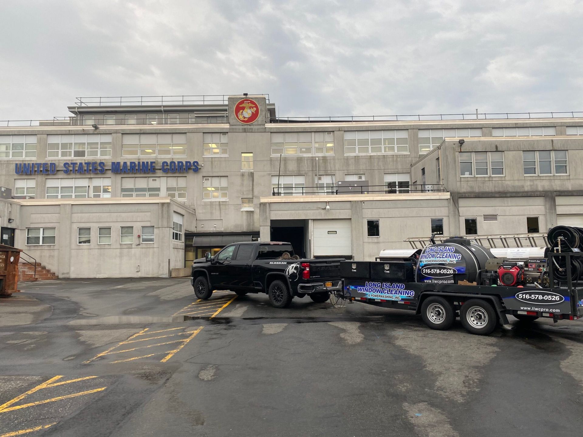 Two trucks are parked in front of a large building.