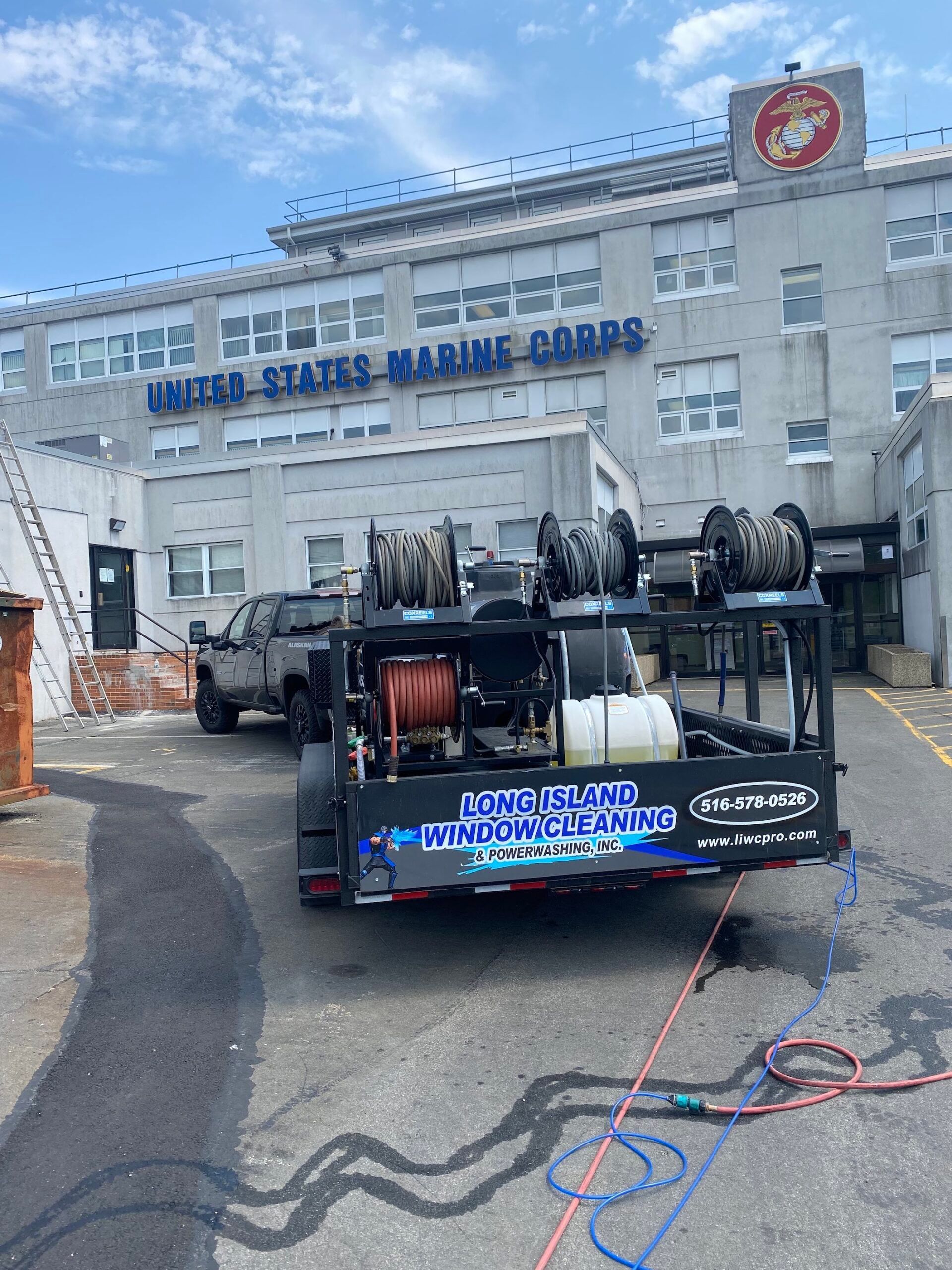 A trailer with a hose attached to it is parked in front of a building.