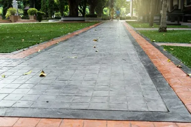A brick walkway in a park surrounded by grass and trees.