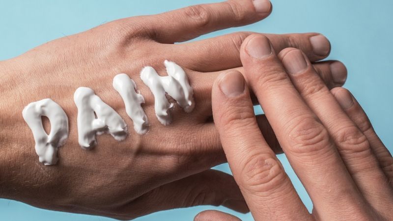 a guy applying pain cream on his hands