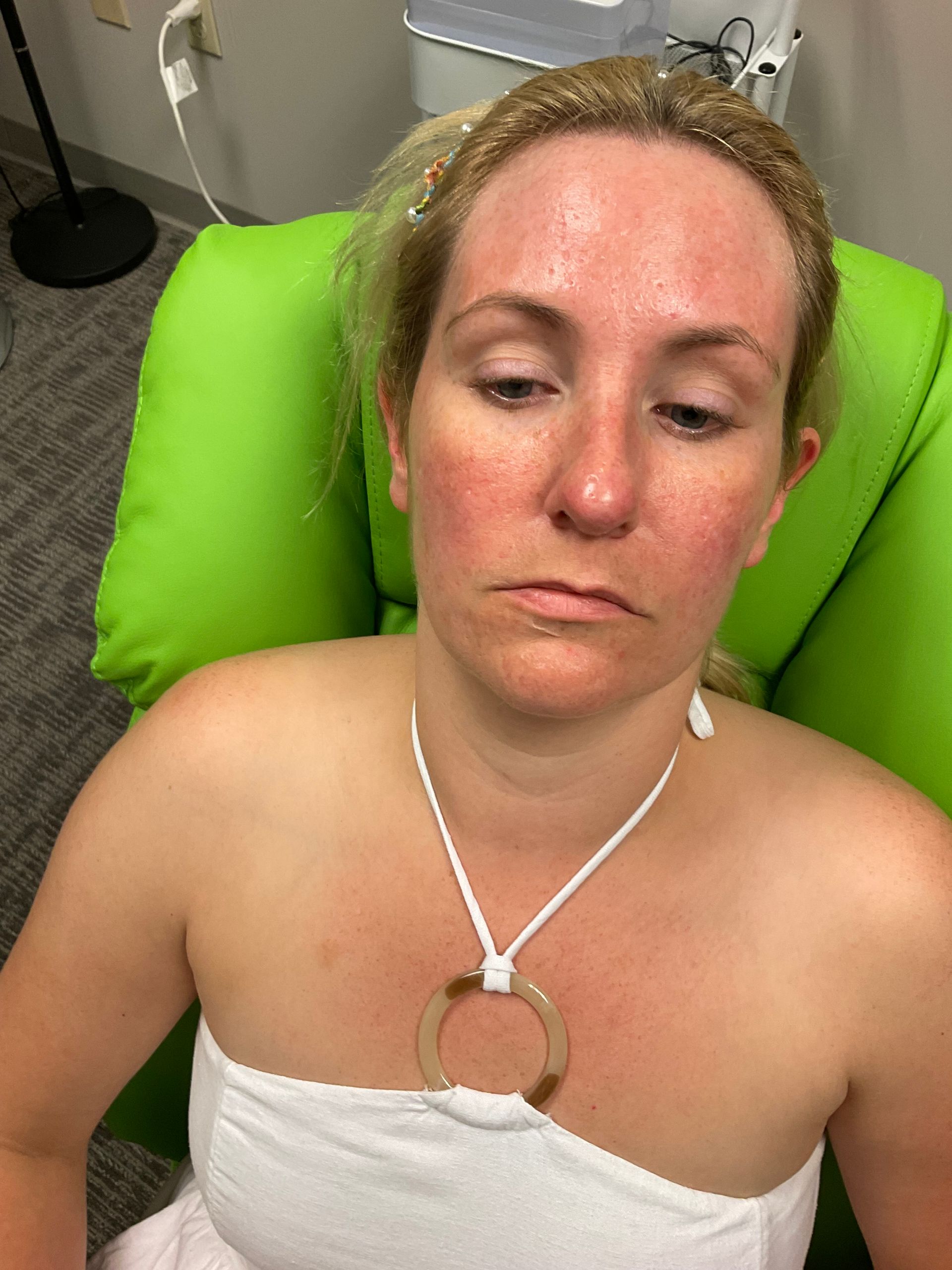 A woman is sitting in a green chair with her eyes closed.