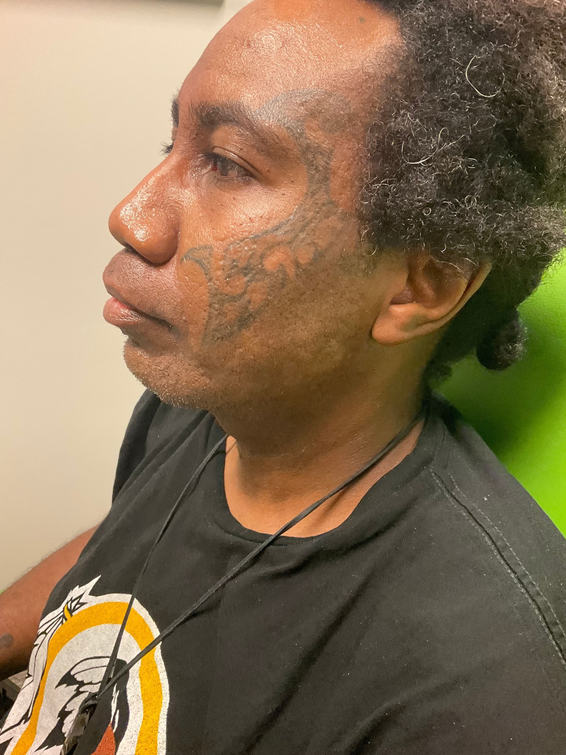 A man with glitter on his face is wearing a black shirt.