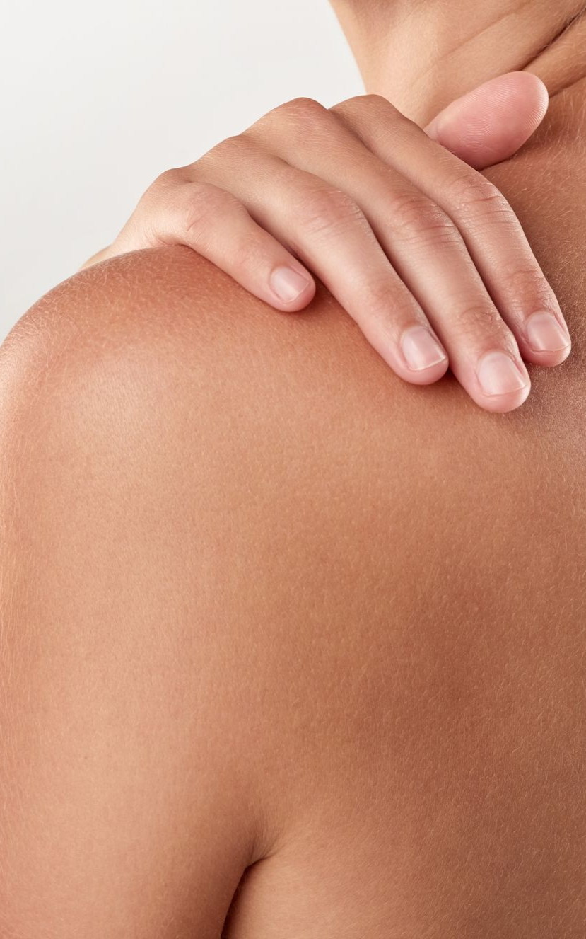 A person's hand on their bare shoulder. Brown skin.