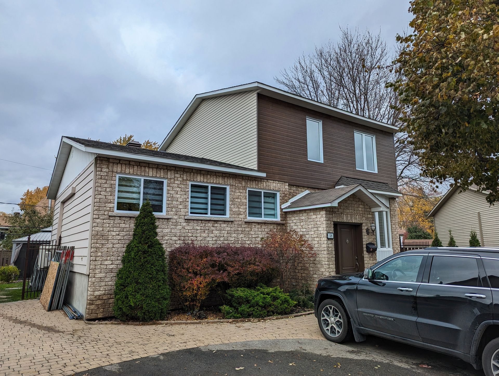 Une voiture est garée devant une maison en brique.