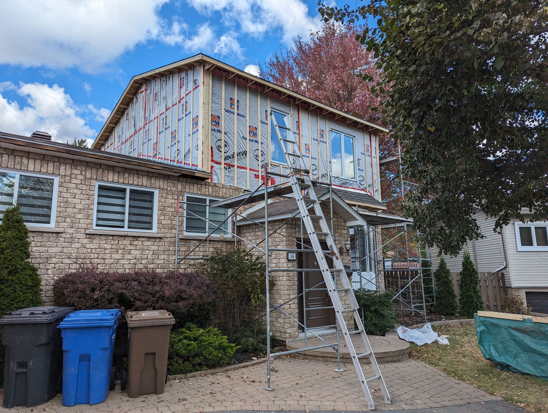 Une maison est en cours de rénovation avec une échelle devant elle.