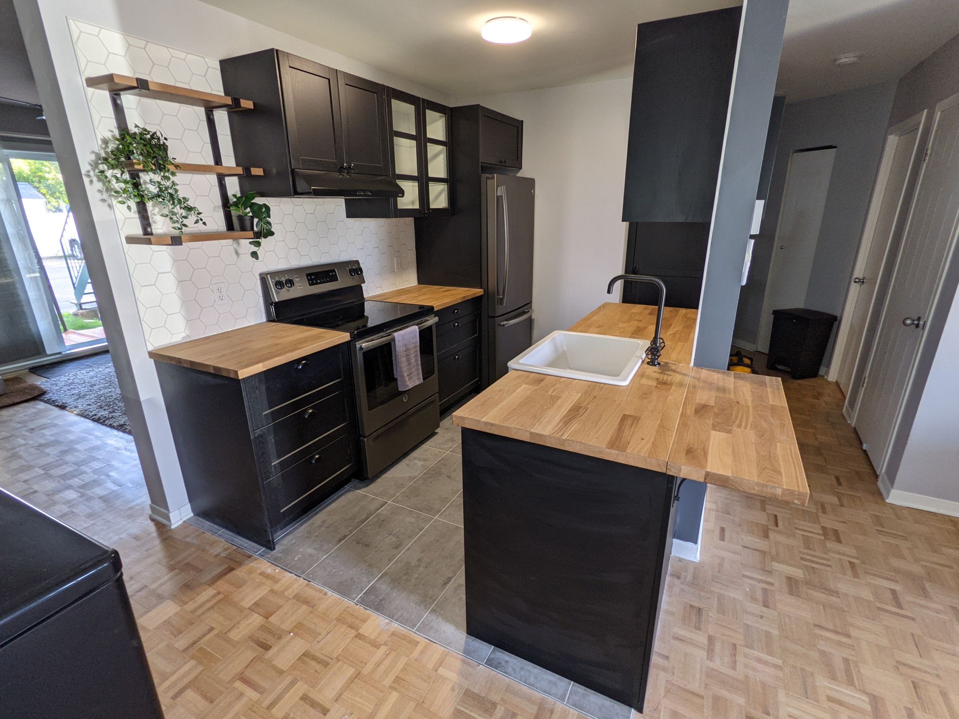 Une cuisine avec armoires noires et comptoir en bois.
