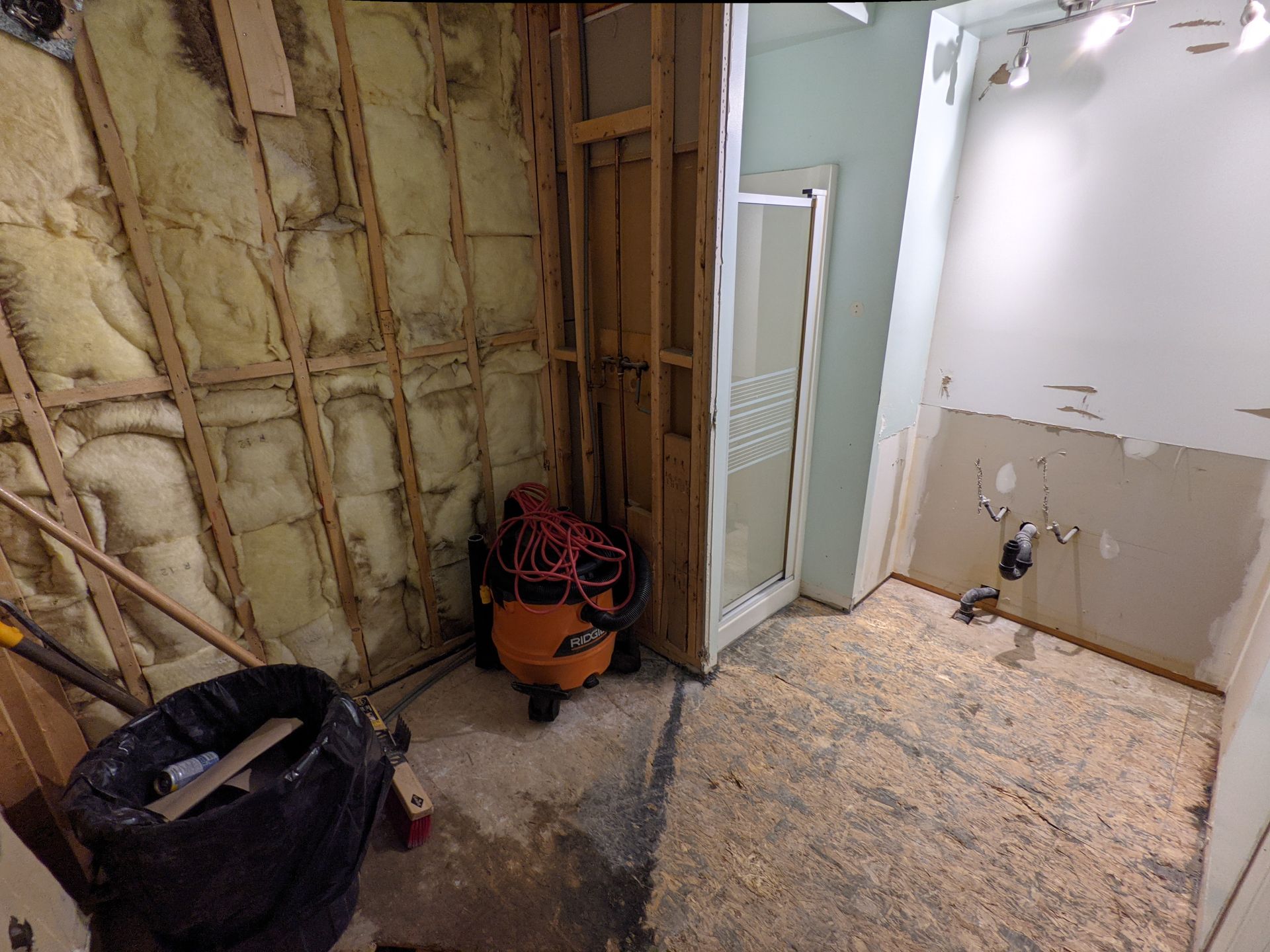 Une salle de bain en construction avec un aspirateur posé au sol.