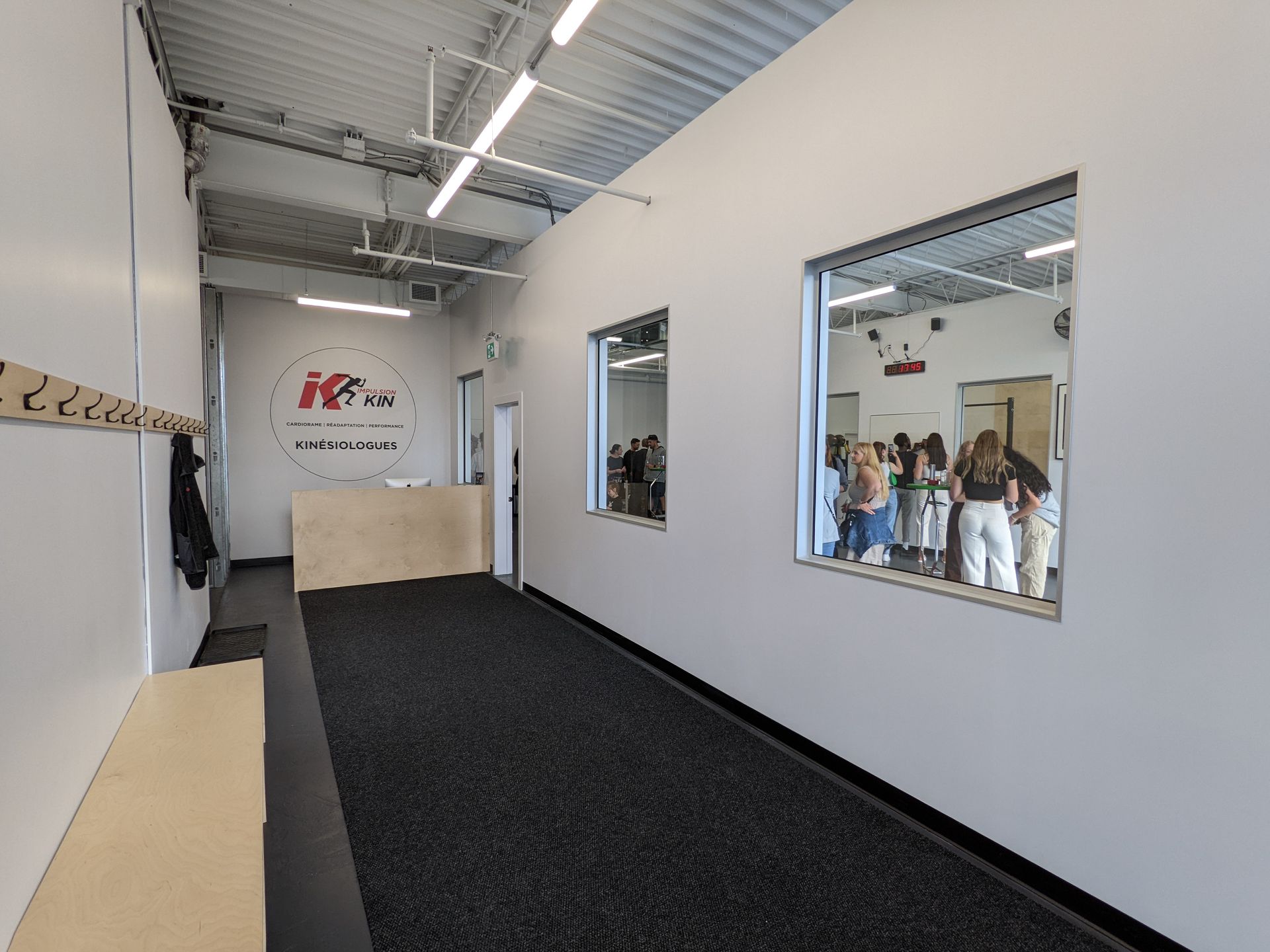 Un couloir dans une salle de sport avec des gens debout devant un miroir.