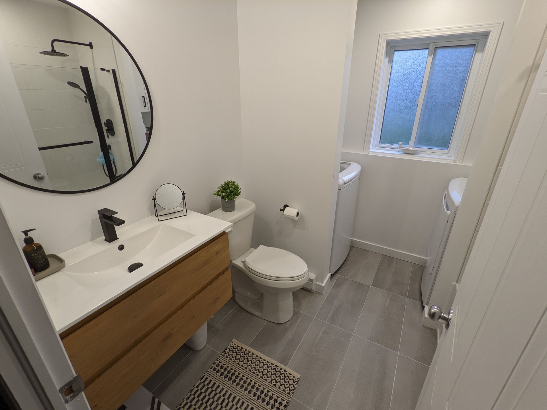 Une salle de bain avec WC , lavabo , miroir et fenêtre.