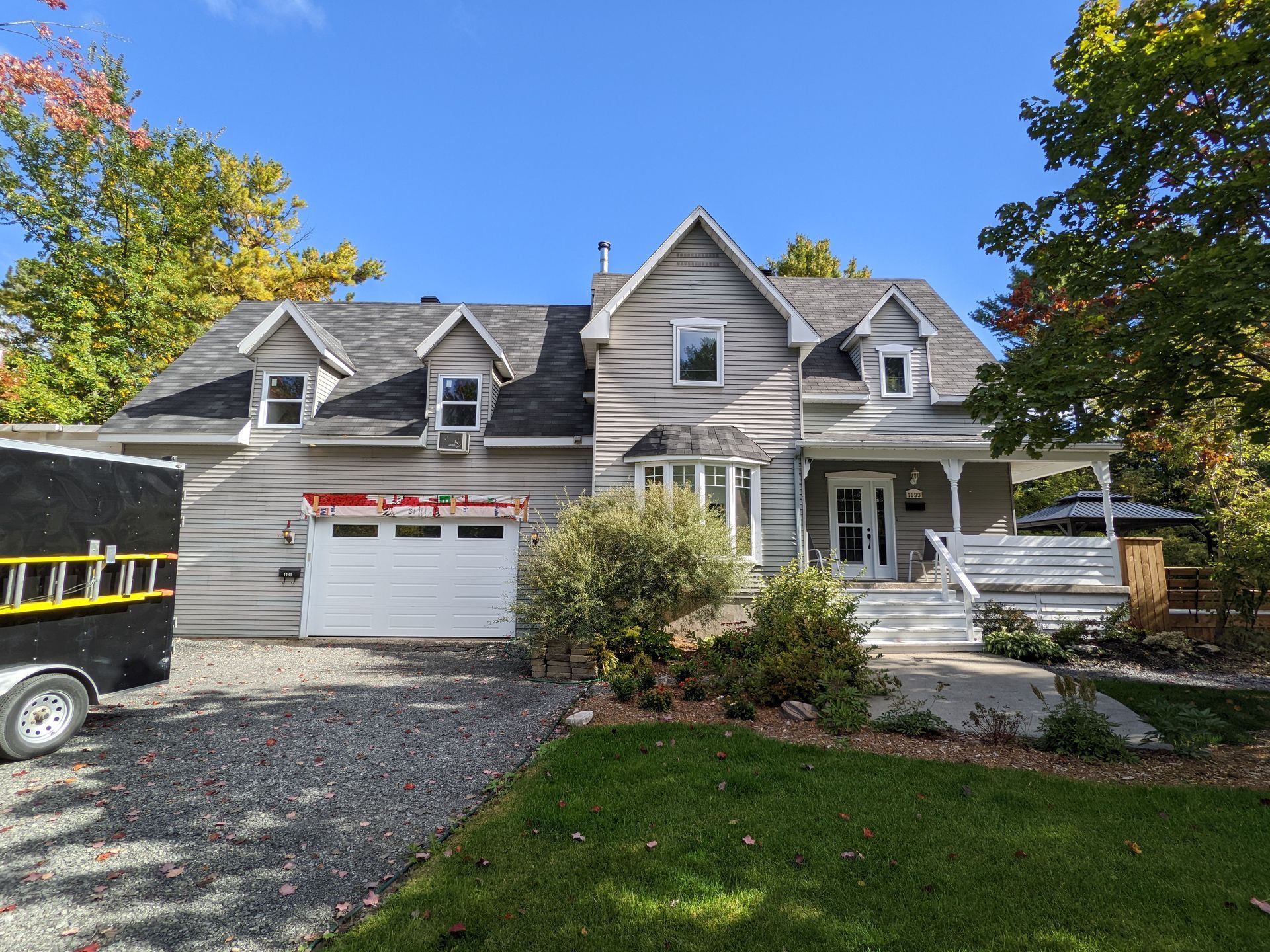 Une grande maison avec une caravane noire garée devant