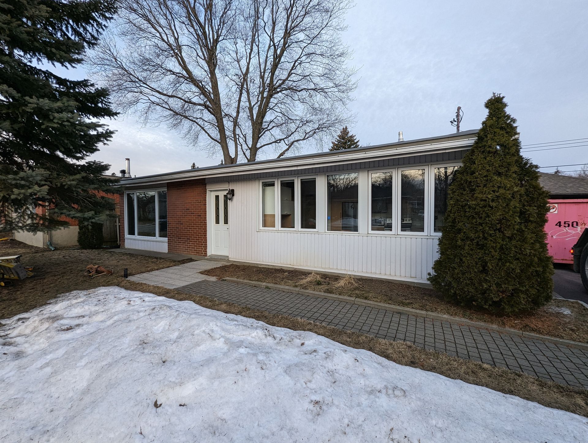 Une maison avec un camion rose garé devant