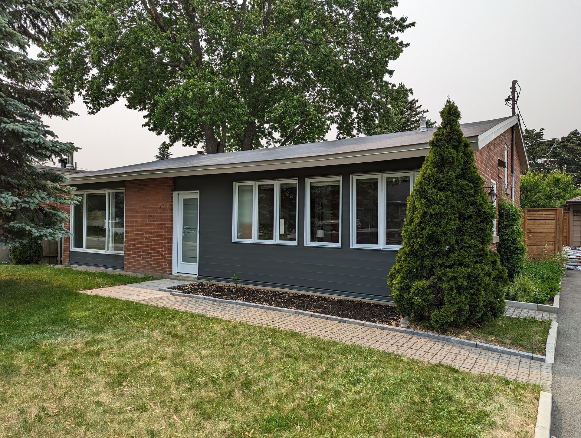 Une petite maison avec beaucoup de fenêtres et d'arbres devant.