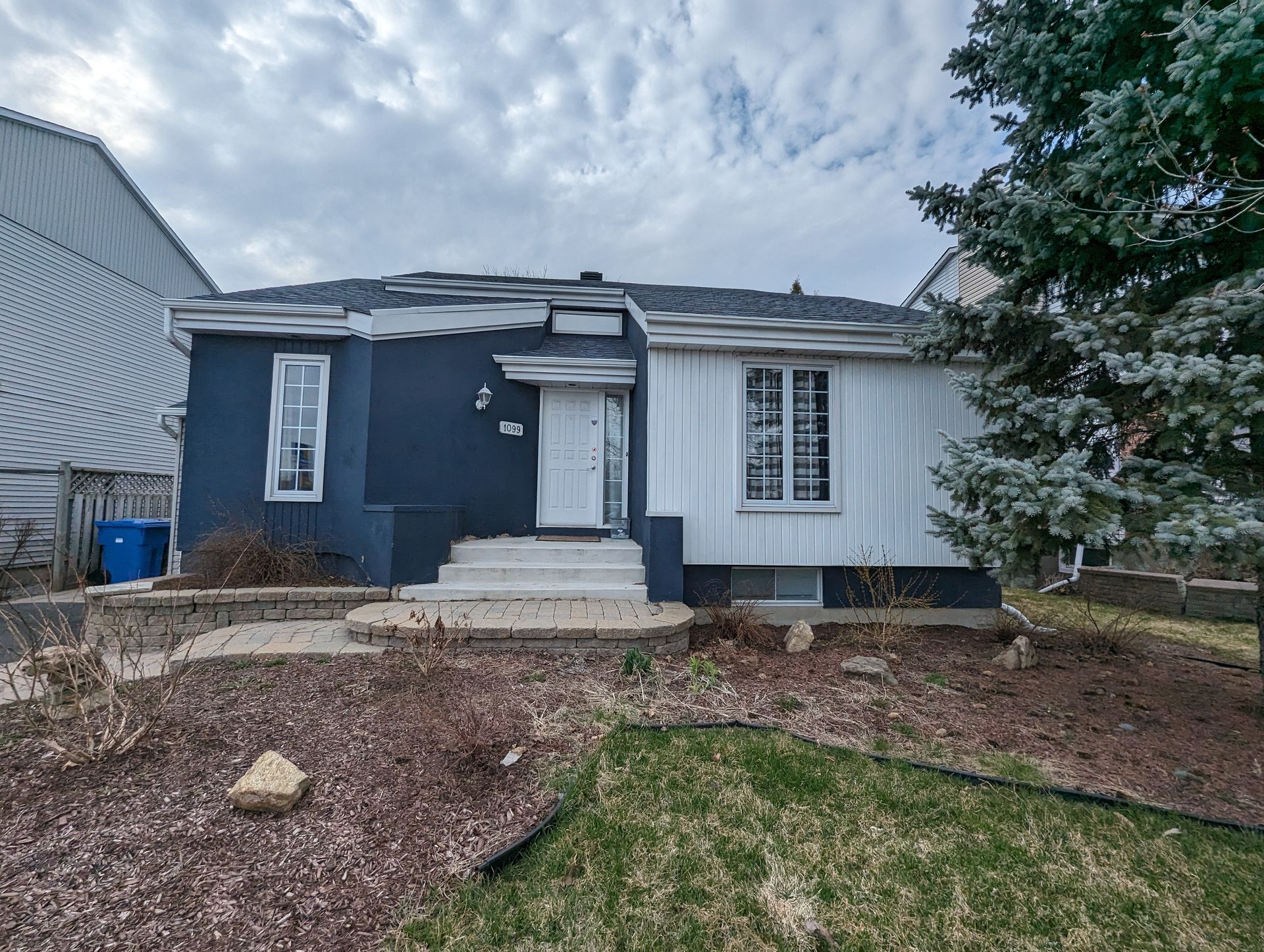 Une maison bleue et blanche avec beaucoup de fenêtres et un arbre devant.