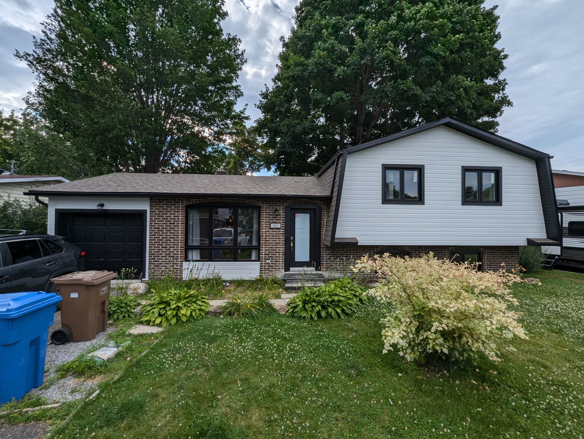 Une maison avec beaucoup d'herbe et d'arbres devant.