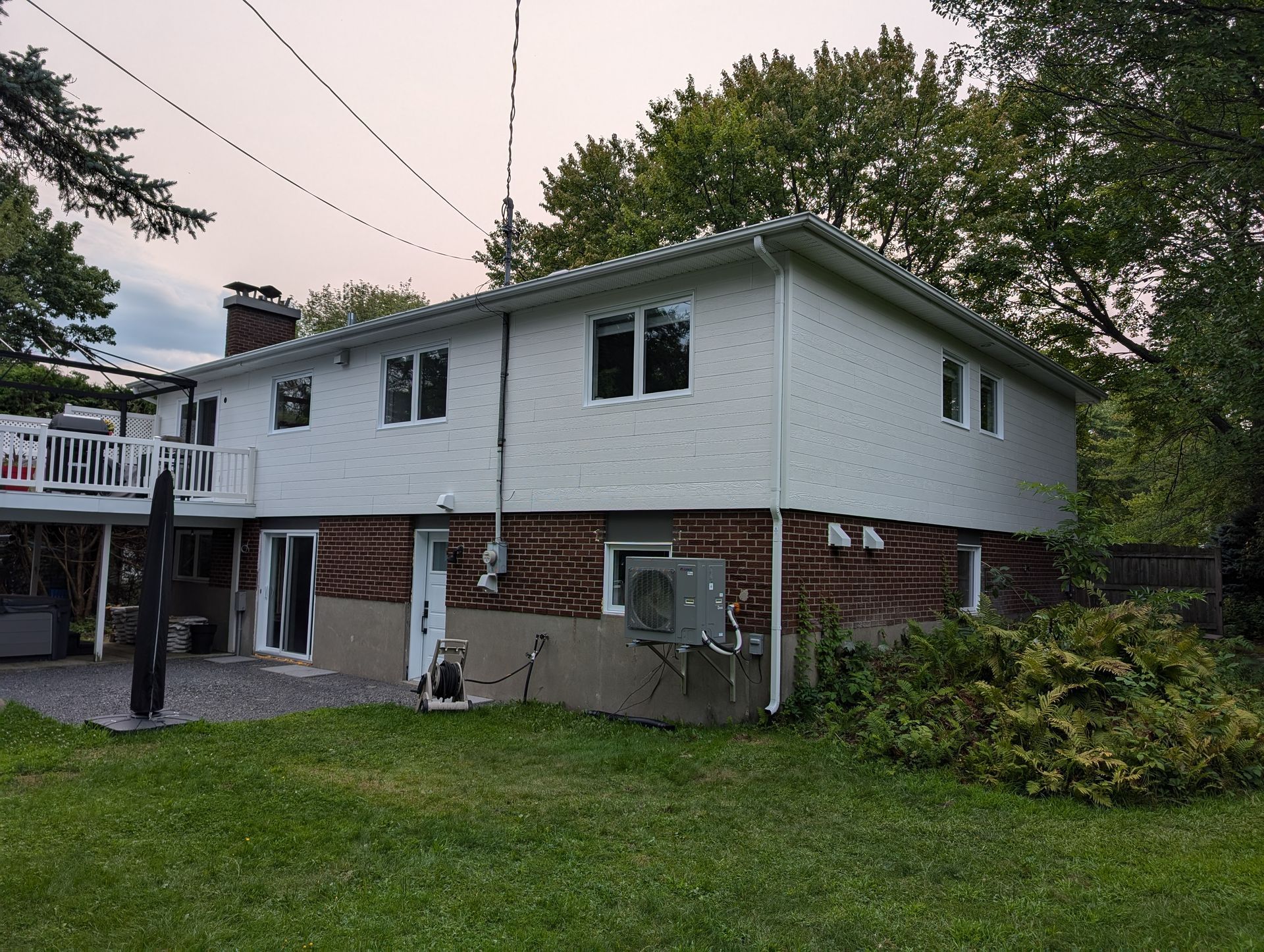 Une grande maison en brique avec un revêtement blanc et une terrasse