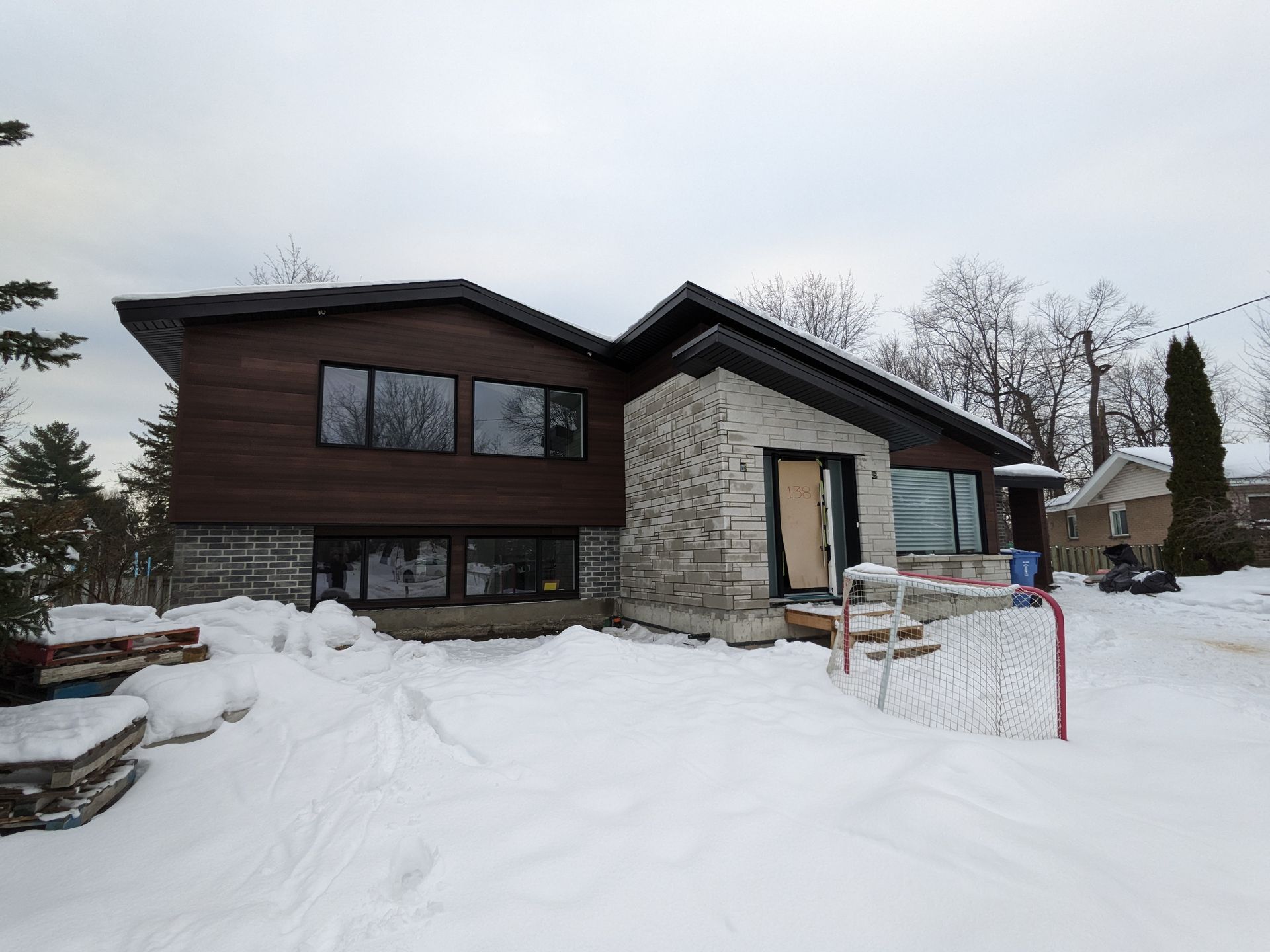 Une maison avec beaucoup de fenêtres est couverte de neige.