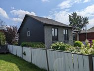 Une petite maison avec une clôture blanche devant elle.