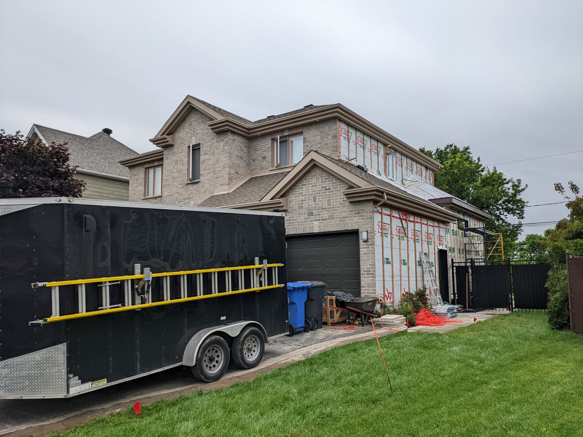 Une remorque avec une échelle attachée est garée devant une maison.