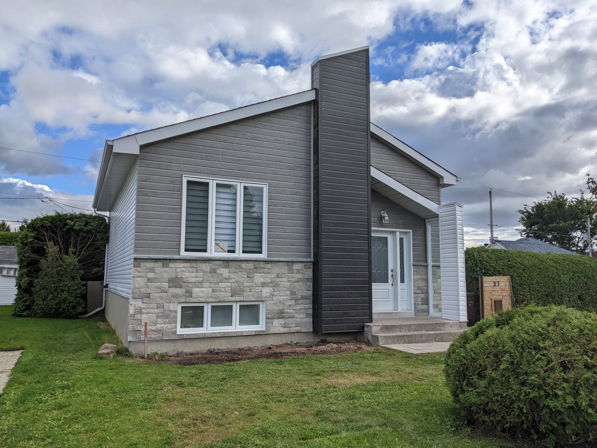 Une petite maison avec une cheminée sur le côté est située au sommet d'une pelouse verte et luxuriante.