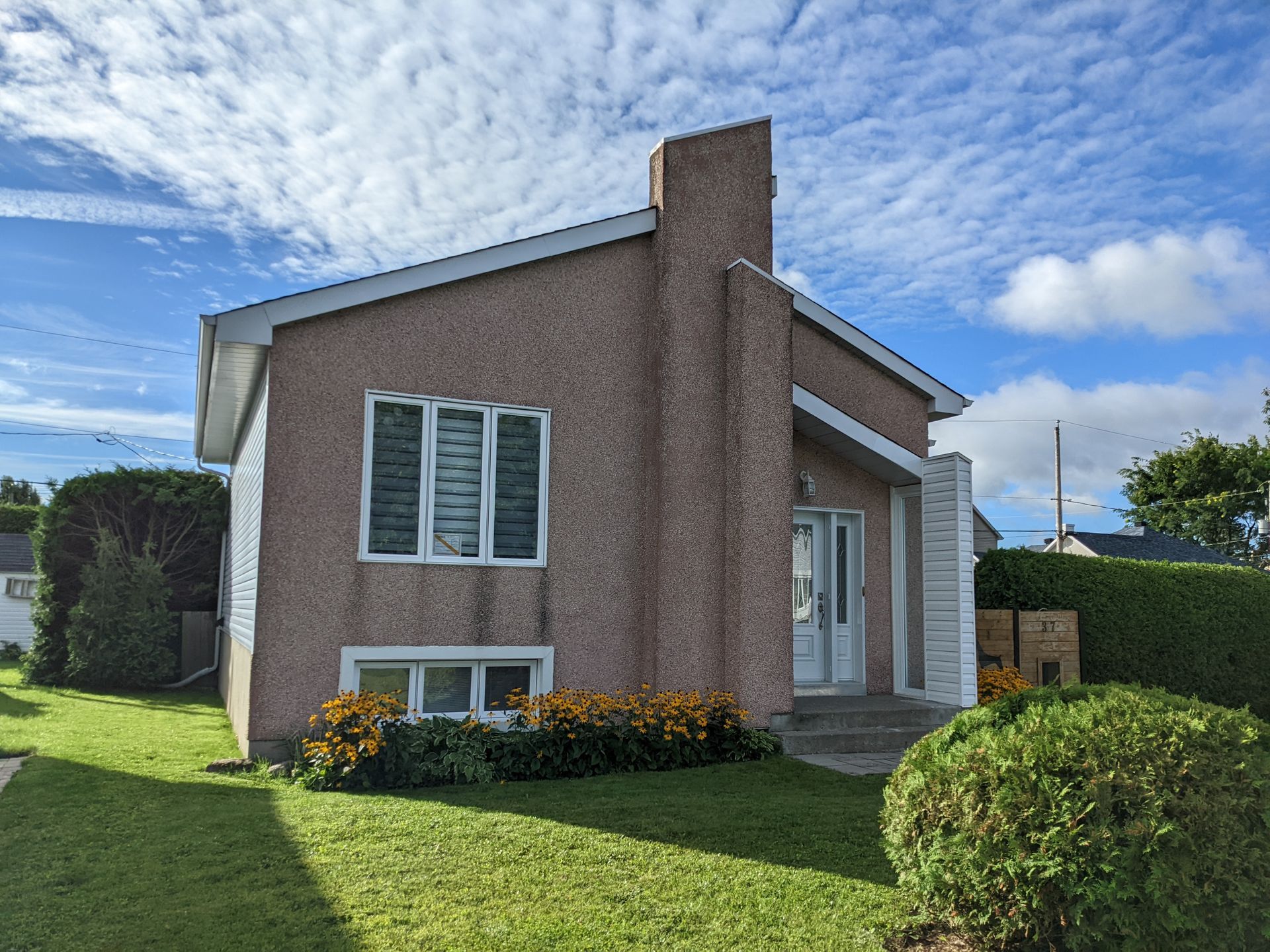 Une petite maison avec une cheminée et une pelouse verte luxuriante devant elle.
