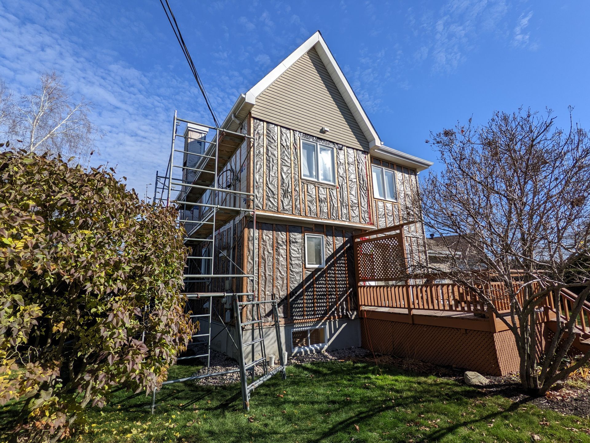 Une maison est en cours de rénovation avec des échafaudages et une terrasse.