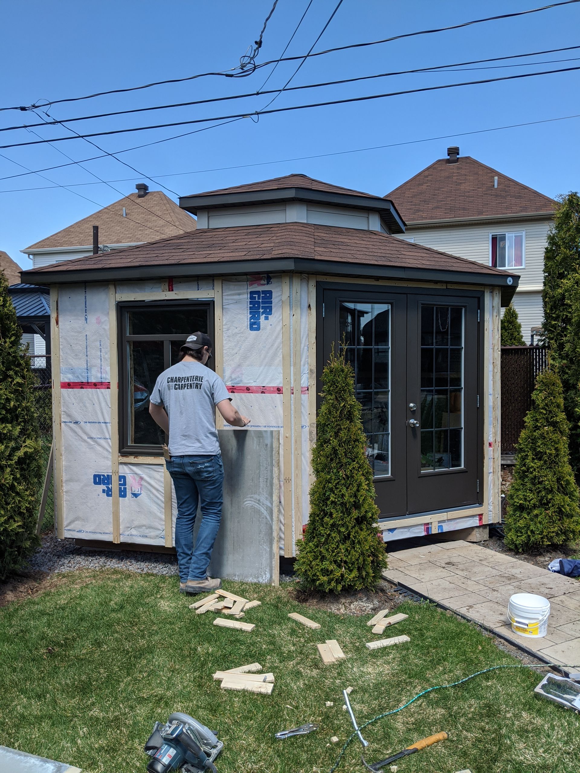 Un homme travaille sur un hangar dans une cour.