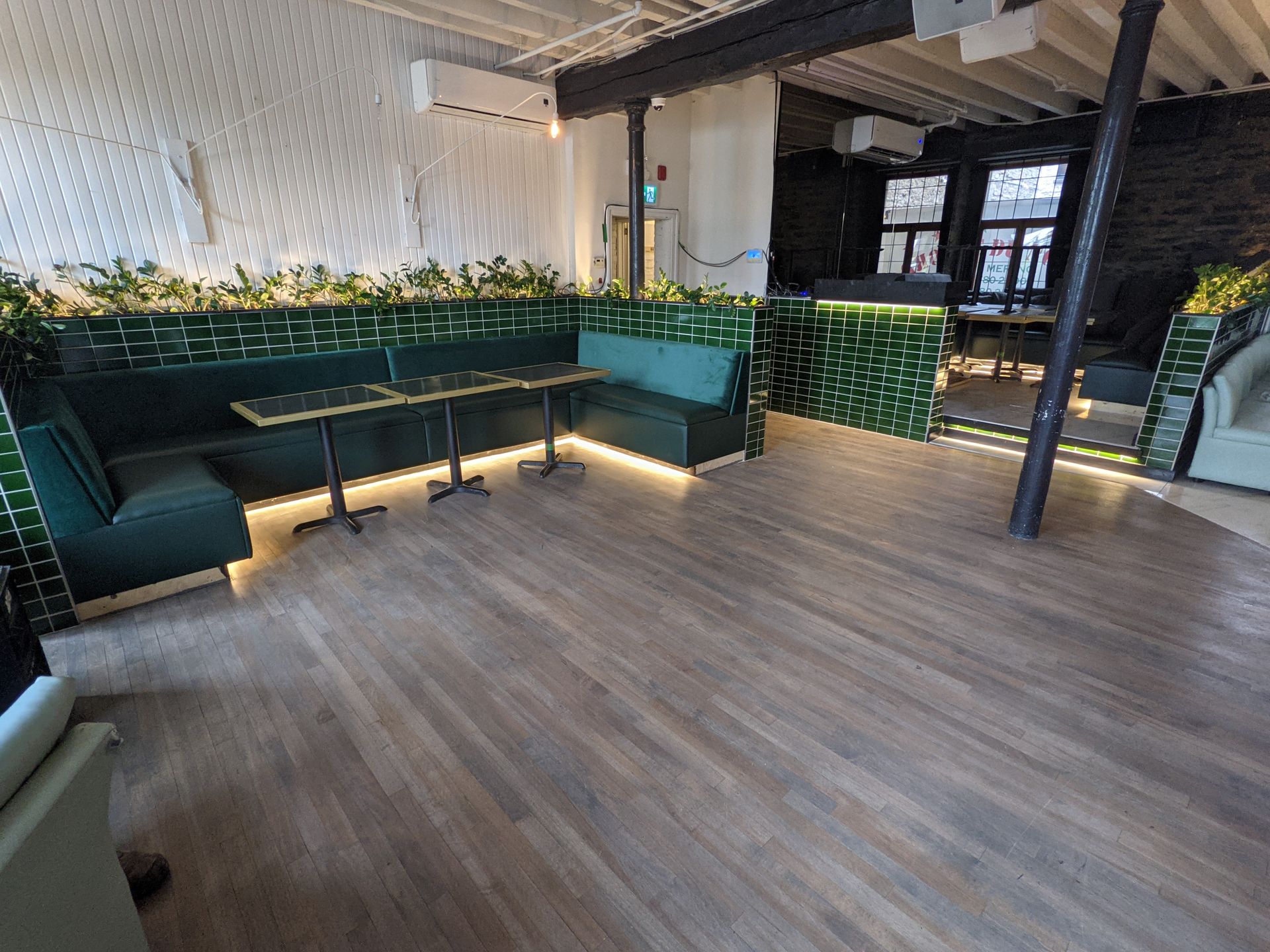 Une grande pièce vide avec parquet et tables en bois.