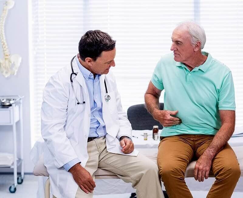 Un médico está hablando con un hombre mayor que está sentado en un banco.