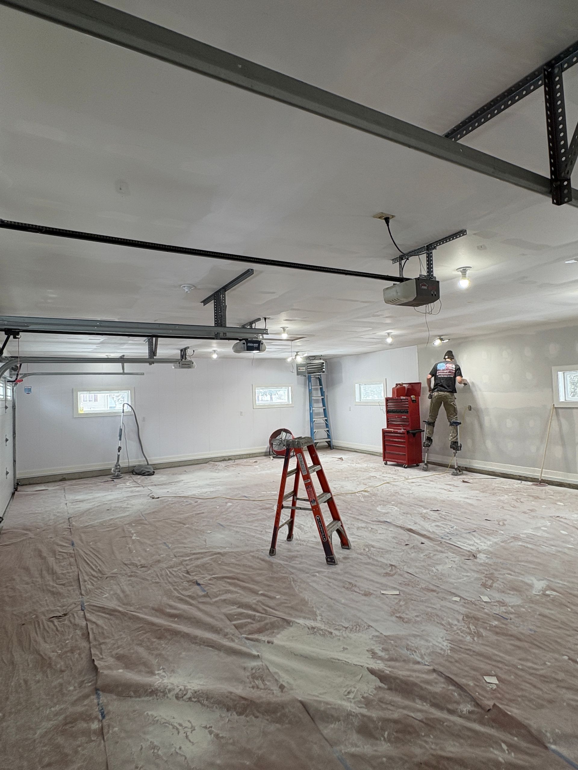 Large garage remodeling with contractor on stilts finishing drywall in Lansing, Iowa.