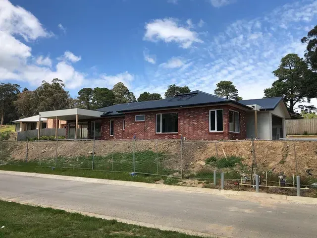 A Brick House With a Blue Roof is Being Built on a Hill — Evoke Building Group In Ballarat Central, VIC