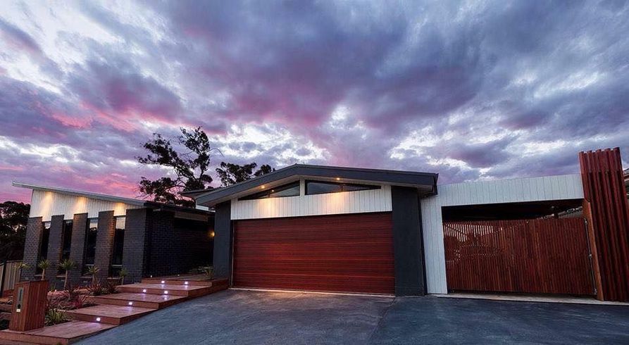 A Modern House With a Red Garage Door and a Sunset in the Background — Evoke Building Group In Ballarat Central, VIC