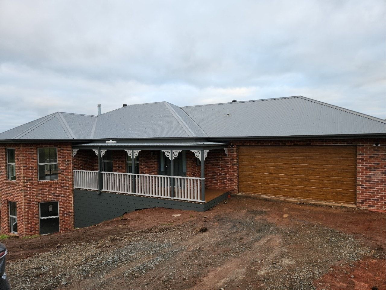 A Brick House With a Garage Door and a Porch — Evoke Building Group In Ballarat Central, VIC