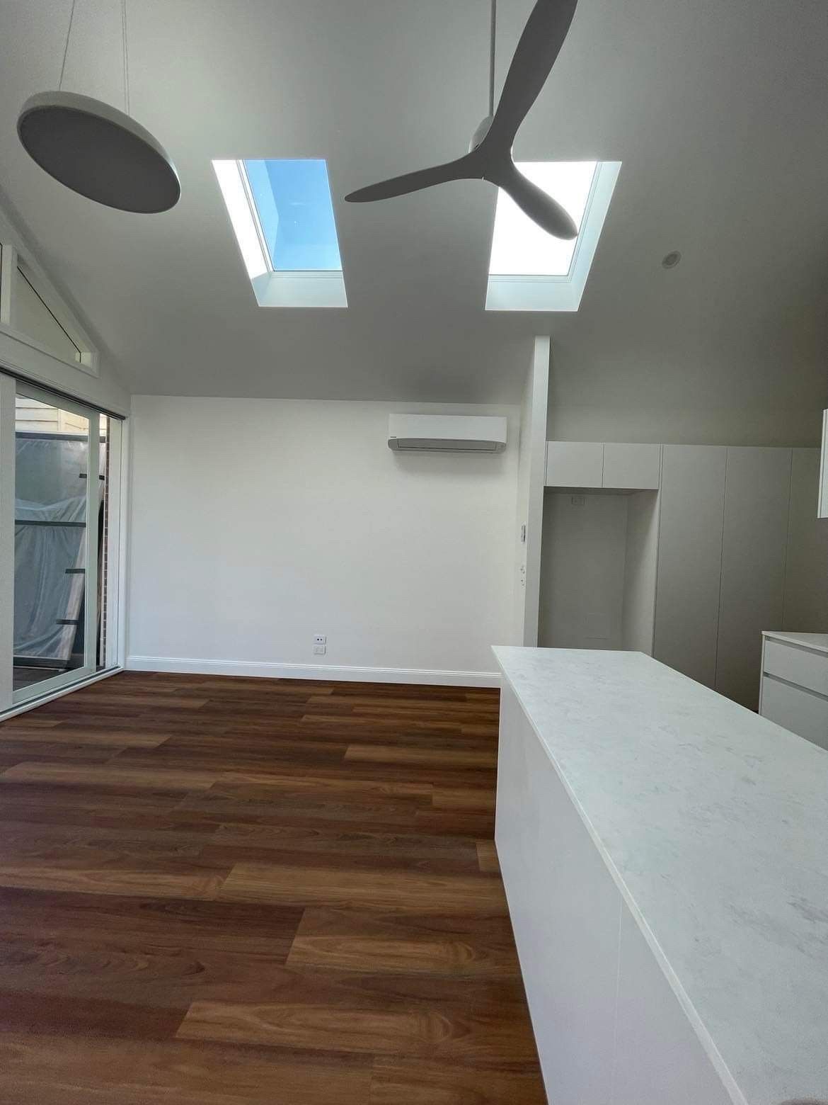 An Empty Living Room With Hardwood Floors and a Ceiling Fan — Evoke Building Group In Ballarat Central, VIC