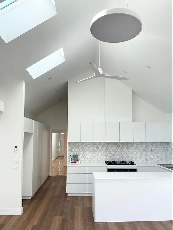 A Kitchen With White Cabinets and a Ceiling Fan — Evoke Building Group In Ballarat Central, VIC