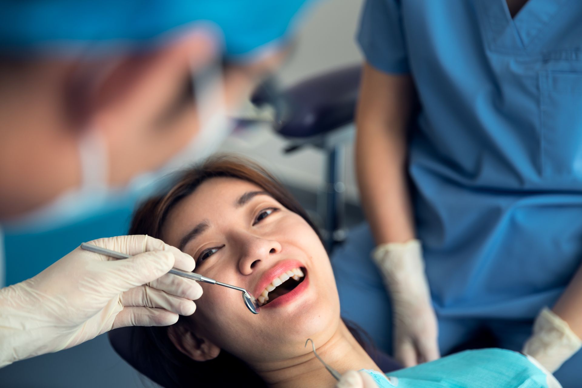 A woman is sitting in a dental chair getting her teeth examined by a dentist.