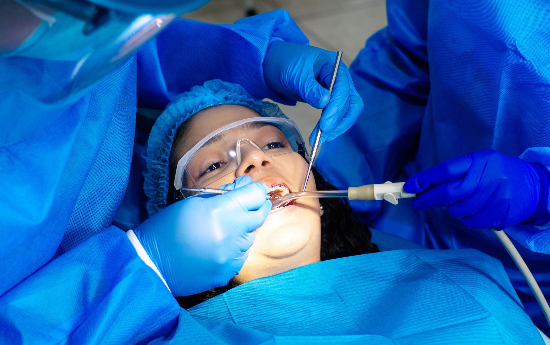 Dentist examining the teeth of a female patient wearing braces at a periodontic dental clinic.