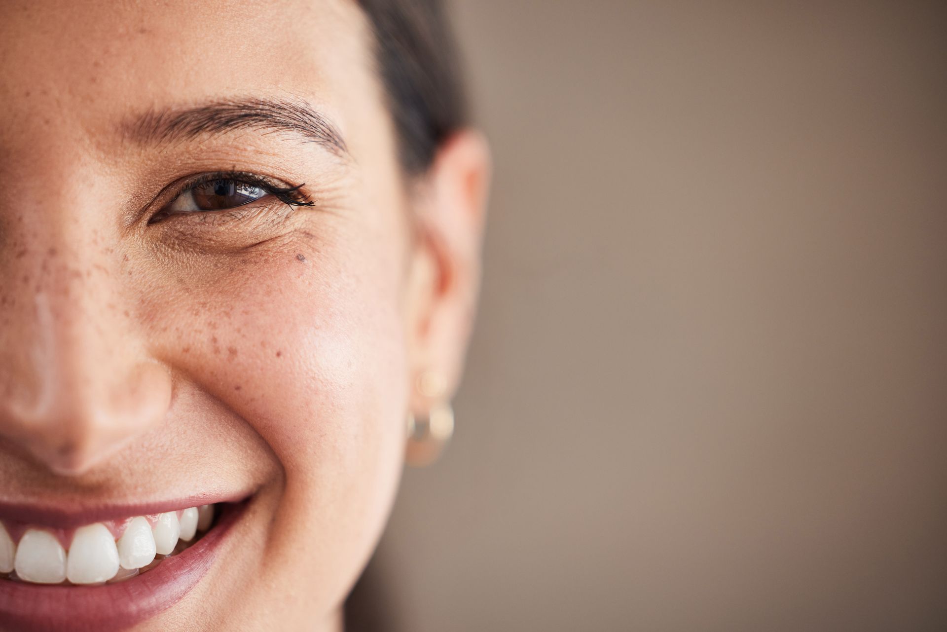 A close up of a woman 's face with freckles smiling.