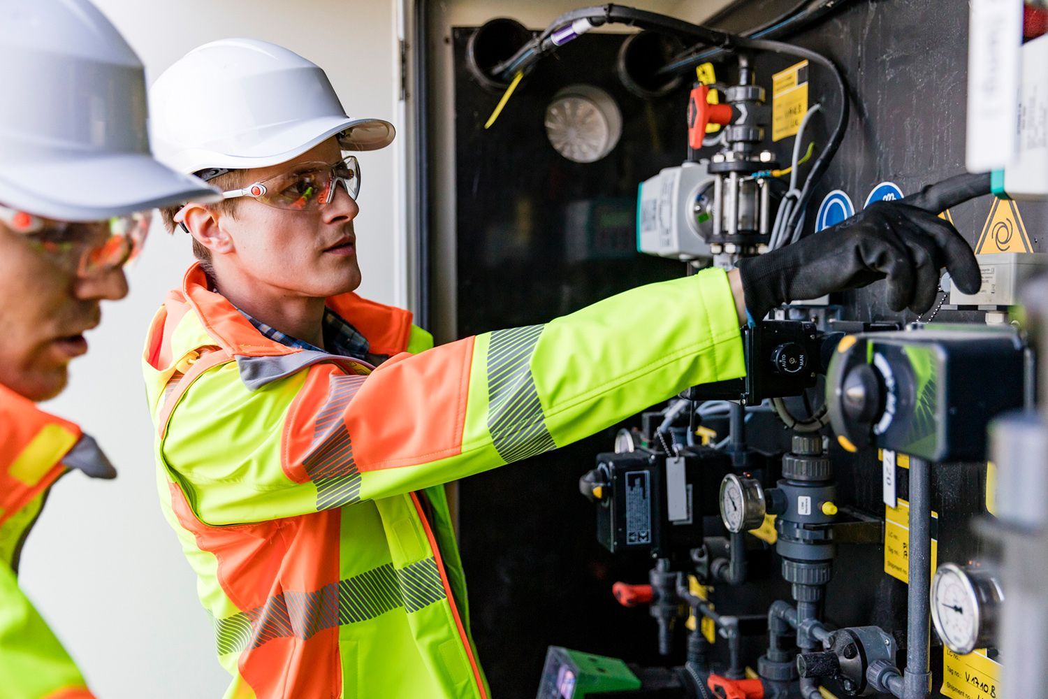 Two men are working on a machine in a factory.